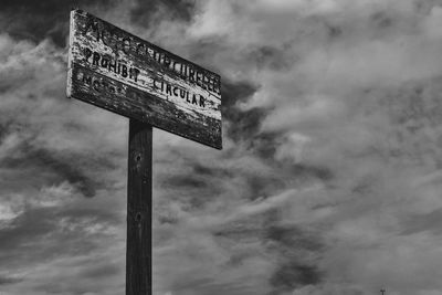 Close-up of road sign against cloudy sky