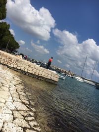 People on pier over sea against sky