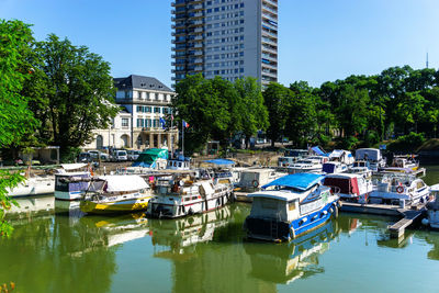 Boats moored on river by trees against sky