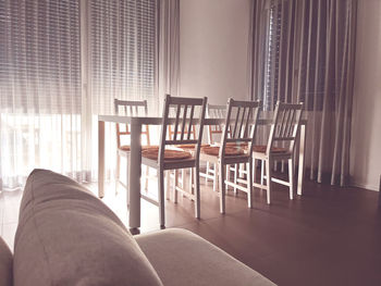 Low section of woman sitting on empty chairs and table at home