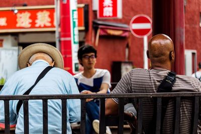 Rear view of men sitting in front of building