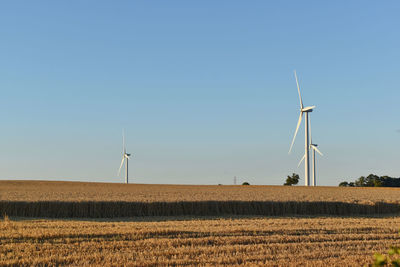 Windmill on field against clear blue sky