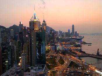 Illuminated buildings in city against sky during sunset