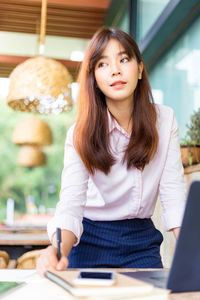 Beautiful young woman using phone while sitting on table