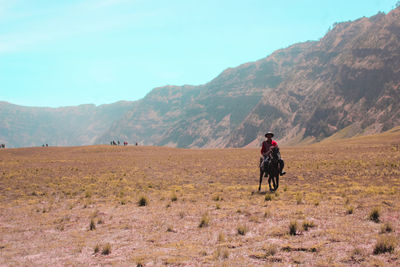 Rear view of man riding motorcycle on field