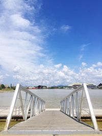 Footbridge over sea against sky