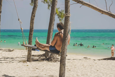 Man sitting on swing at beach