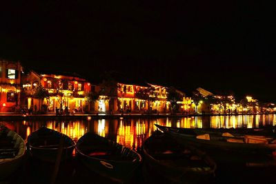 Boats moored at illuminated harbor against clear sky at night