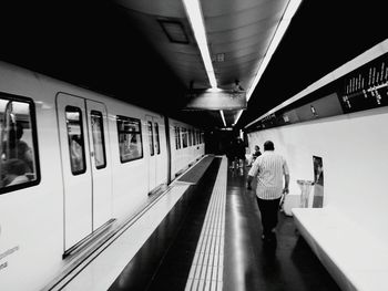 Rear view of man walking at railroad station platform