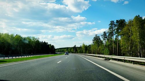 Empty road with trees in background