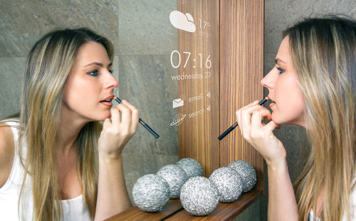 Woman applying lipstick while looking into mirror