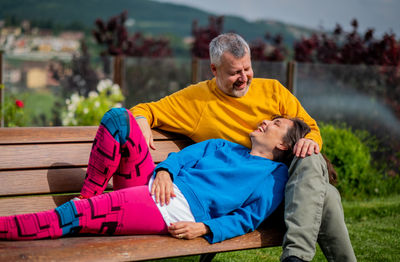Full length of couple relaxing on bench at park