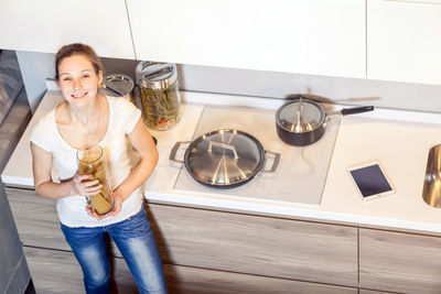 Portrait of a smiling young woman holding camera at home