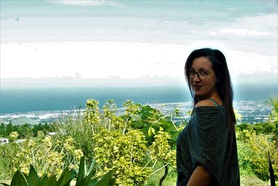 Beautiful young woman standing on land against sky