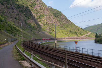 Railroad tracks by mountain against sky