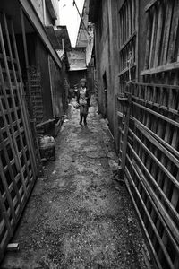 Woman walking in alley amidst buildings
