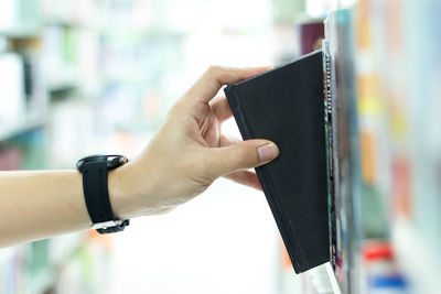 Woman picking book from shelf in library