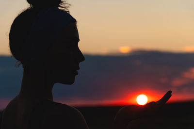 Silhouette woman against orange sky during sunset