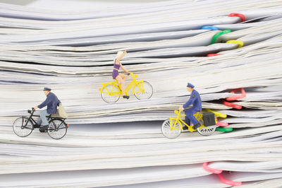 Close-up of figurines riding bicycles on stacked files