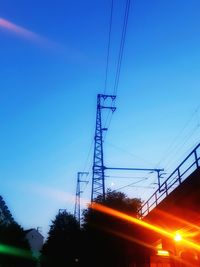 Low angle view of electricity pylon against blue sky