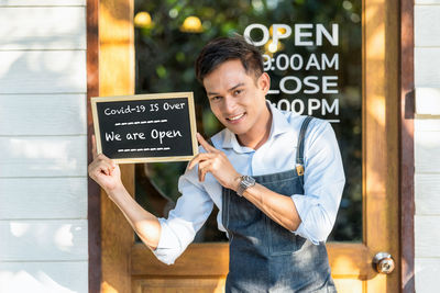 Asian partner small business owner hands holding and showing the chalkboard with wording covid-19 