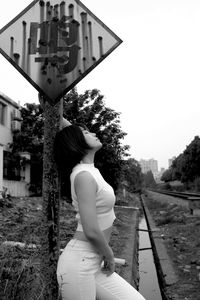 Rear view of woman standing against sky in city