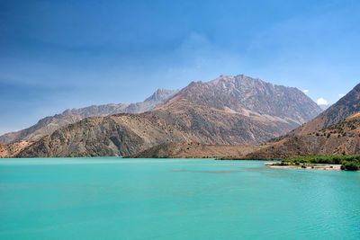 Scenic view of lake and mountains against blue sky