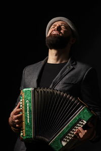 Portrait of young man playing on accordeon.