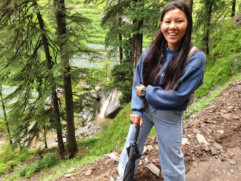 Portrait of smiling young woman standing in forest