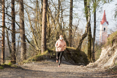 Full length of woman wearing mask exercising at park