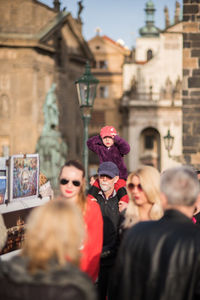 Rear view of people standing against buildings in city