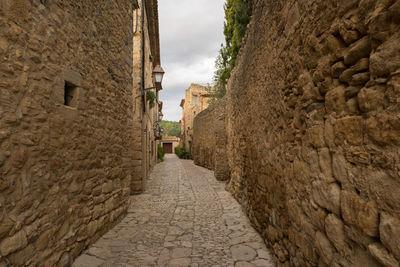 Footpath amidst stone wall against sky