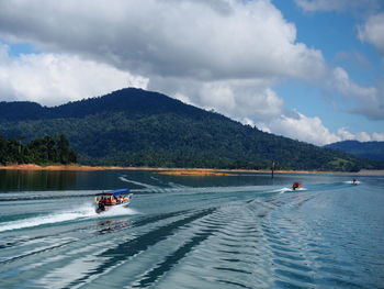 People on boat in lake against sky