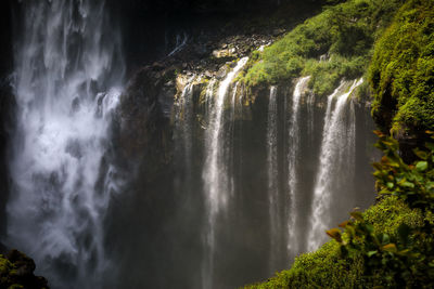 Scenic view of waterfall in forest against sky