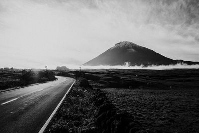 Road leading towards mountains against sky