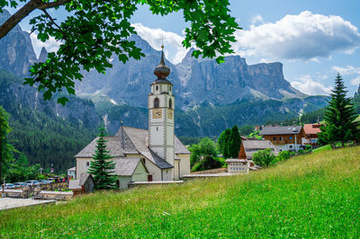 Built structure by trees and buildings against sky