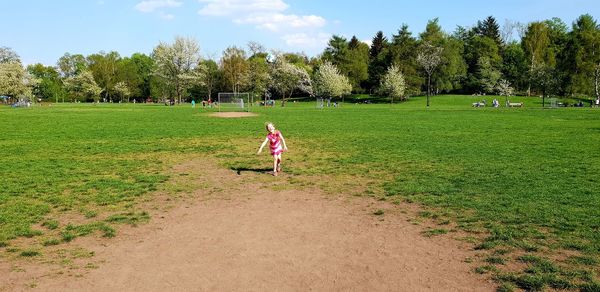 Children playing on field against trees