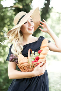 Smiling woman looking away while holding fruits in basket