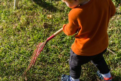 Faceless toddler raking the yard