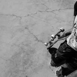 Low section of man holding skateboard while standing outdoors