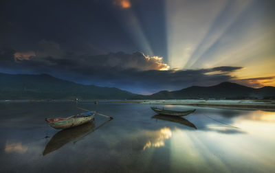 Boats moored in sea against sky during sunset