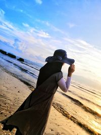 Rear view of person on beach against sky