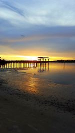 Pier over sea against sky during sunset