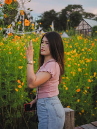 Side view of a beautiful young woman standing by plants