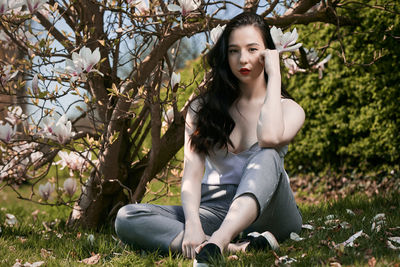 Portrait of woman sitting against blooming flowers