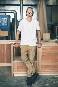 Portrait of carpenter laughing while standing at workshop