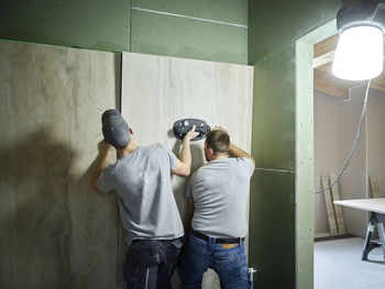 Tilers installing tiles on wall with vacuum cup at construction site