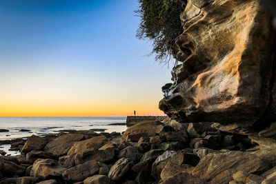 Rock formation on beach against sky during sunset