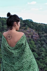 Rear view of young woman standing against sky