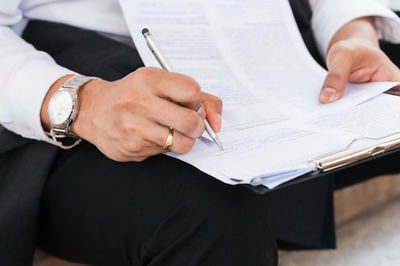 Midsection of man holding paper at home